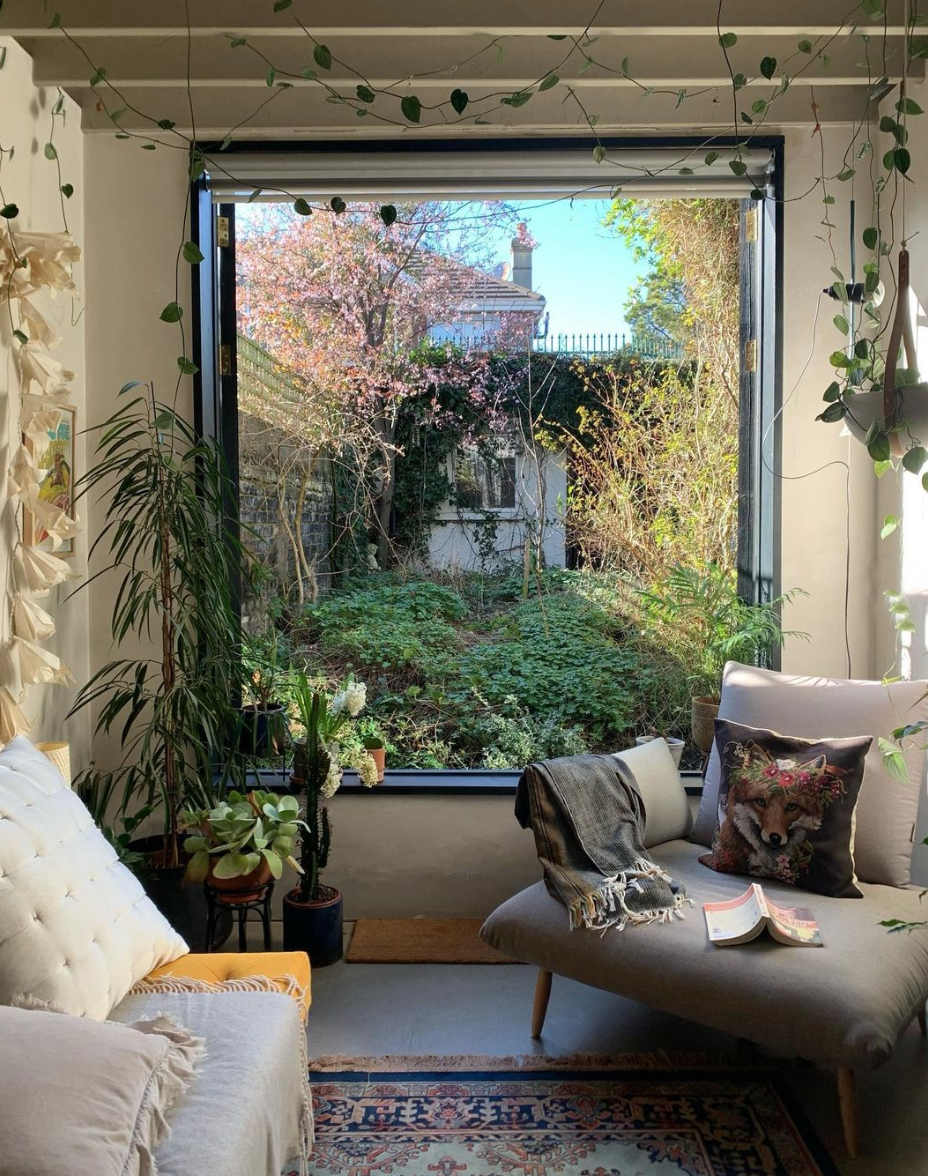 large picture window into garden, framed by houseplants