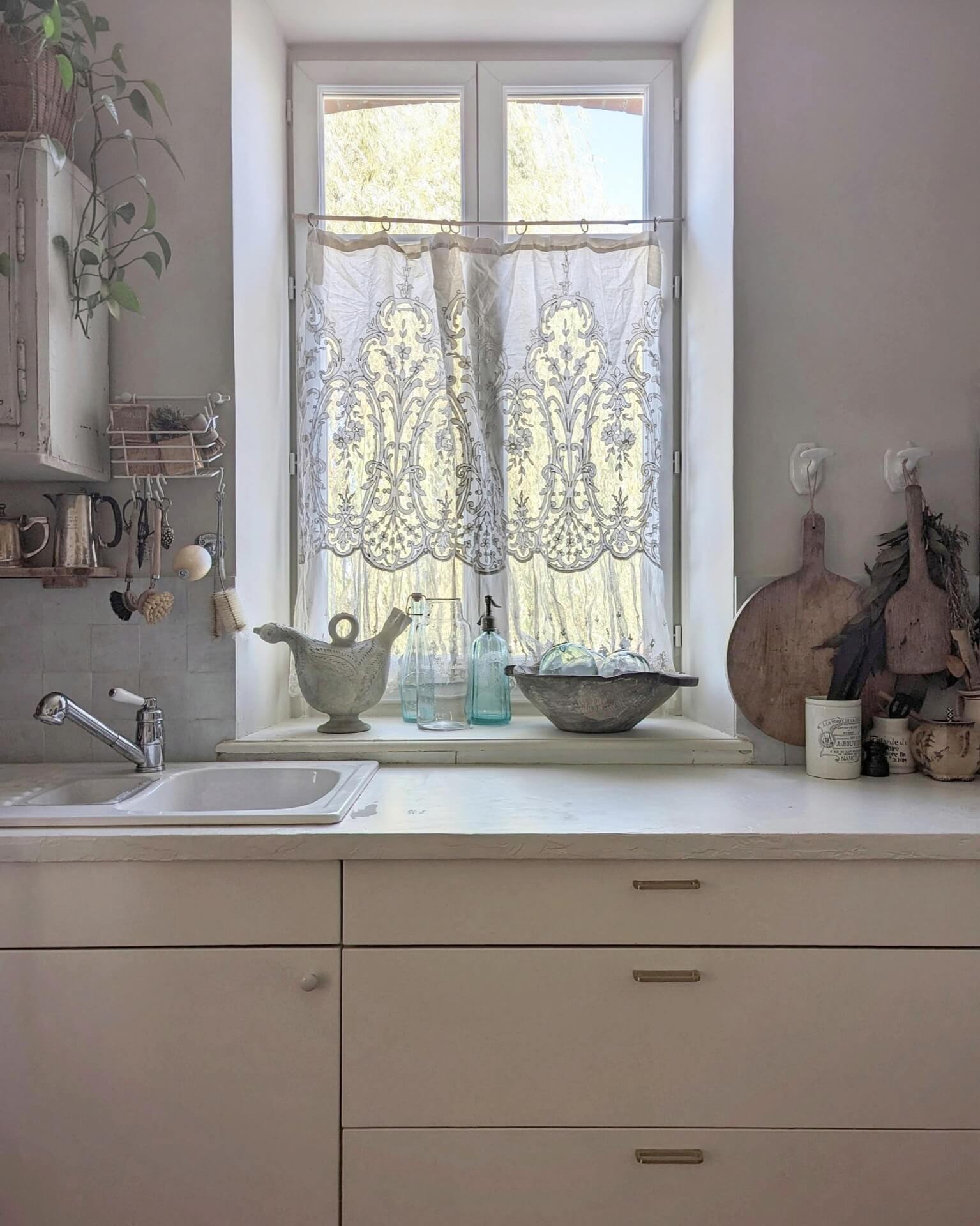 Kitchen with lace curtain and old wooden chopping boards and vintage decor